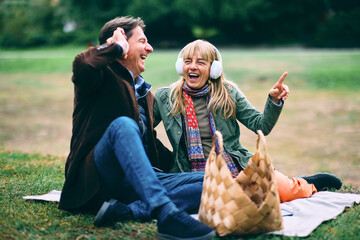 Mature couple enjoying music and laughing in park