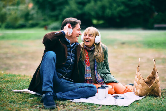 Fototapeta Couple listening to music and laughing in park
