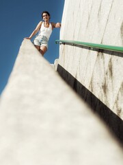 A smiling young girl stands at the top of the lighthouse stairs with sunlight and a clear sky in the background.