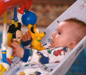 Baby in chair  playing with hanging toys