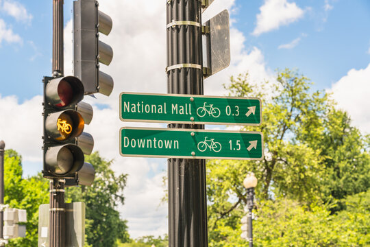 A bike traffic light glows beside directional signs pointing toward the National Mall and Downtown