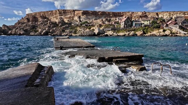 Wavees breaking on the shore oposite Popeye Village, Malta. High quality 4k footage