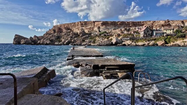 Wavees breaking on the shore oposite Popeye Village, Malta. High quality 4k footage