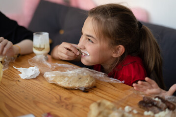 Happy family enjoying eating at home, girl with milk mustache smiling playfully, cozy family moment.