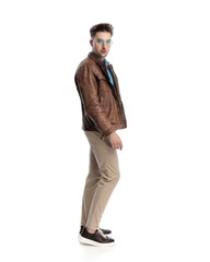 side view of sexy young man in brown leather jacket standing