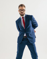 cool fashion man in navy blue suit posing with hands behind