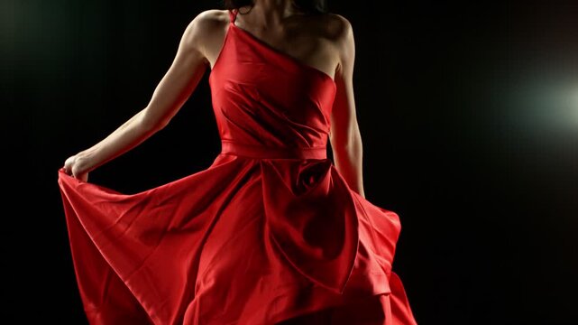Stunning Woman in Ruby Red Dress Gracefully Posing Against a Black Background, Captured in Super Slow Motion with Camera Panning for Better Dramatic Effect. Closeup, Detail. 