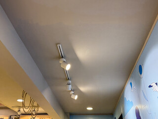 A lighted ceiling with a blue and white mural on the wall