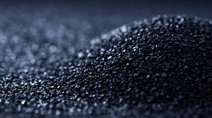 Black granular activated carbon close up showing textured shiny particles and shallow depth of field evoking industrial purification and filtration