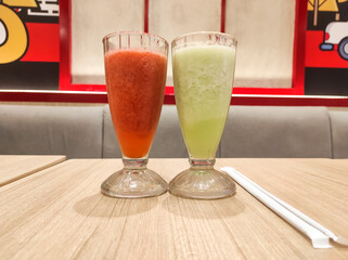 Beverage photography themes. A glass of strawberry juice and a glass of melon juice photographed side by side at a fast food restaurant. Cold juice beverage dish. Graphic Resources