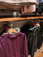 Parachute jackets hanging in a store display cabinet. Jackets in various colors for sports in a clothing store. Shopping in a department store. Fashion and lifestyle photography themes.