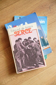 Three books on a wooden floor, with 'Serce' by Edmund de Amicis prominently displayed on top of travel guides.