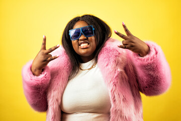 Image of a beautiful woman posing in a furry coat on a yellow background