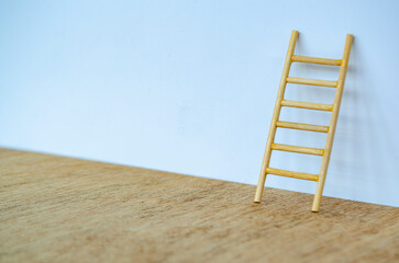 Wooden ladder standing tall against a white cover with customizable space for text or ideas.