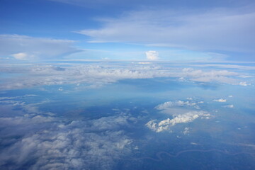 Beautiful white clouds drifting peacefully in the blue sky as seen from above or Layers of soft clouds stretching across the sky during a daytime flight.