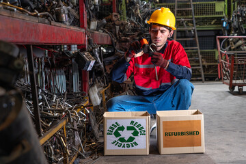 Male staff wearing helmet uniforms select raw materials and car parts for reuse or recycle waste car parts in the auto parts store warehouse.