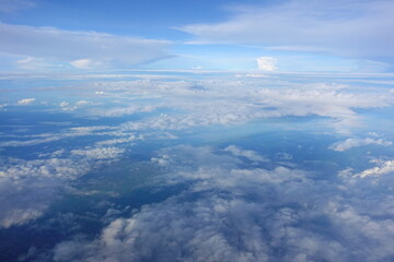 Beautiful white clouds drifting peacefully in the blue sky as seen from above or Layers of soft clouds stretching across the sky during a daytime flight.