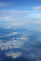 Beautiful white clouds drifting peacefully in the blue sky as seen from above or Layers of soft clouds stretching across the sky during a daytime flight.