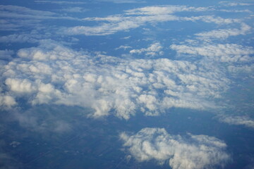 Beautiful white clouds drifting peacefully in the blue sky as seen from above or Layers of soft clouds stretching across the sky during a daytime flight.