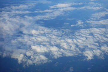 Beautiful white clouds drifting peacefully in the blue sky as seen from above or Layers of soft clouds stretching across the sky during a daytime flight.