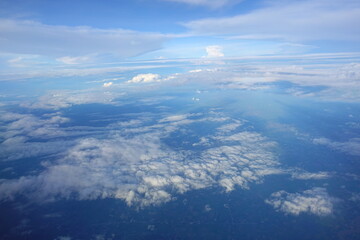 Beautiful white clouds drifting peacefully in the blue sky as seen from above or Layers of soft clouds stretching across the sky during a daytime flight.