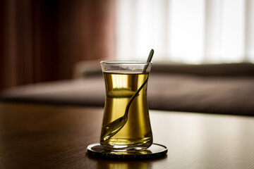 cup of tea on a table with a spoon inside and a coaster
