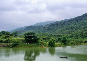 Serene lake reflecting lush green mountains under a cloudy sky