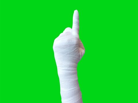 Mummy hands wrapped in a bandage. pointing hand gesture. Index finger pointing to something, attention, direction. isolated on a green background. Halloween concept. - Powered by Adobe