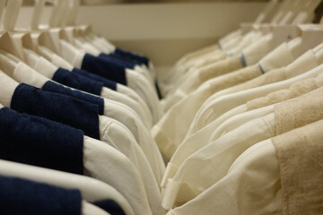 Soft pastel pink blue yellow cream baby clothes neatly arranged on white plastic hangers in a boutique store, highlighting delicate embroidery and gentle cotton texture for newborn girls.
