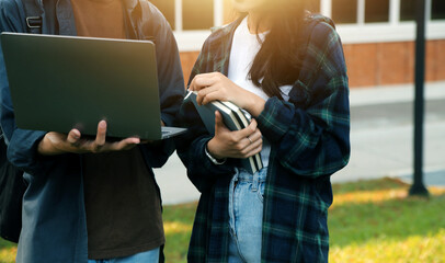 Happy students walking together on university campus, chatting and laughing outdoors after classes