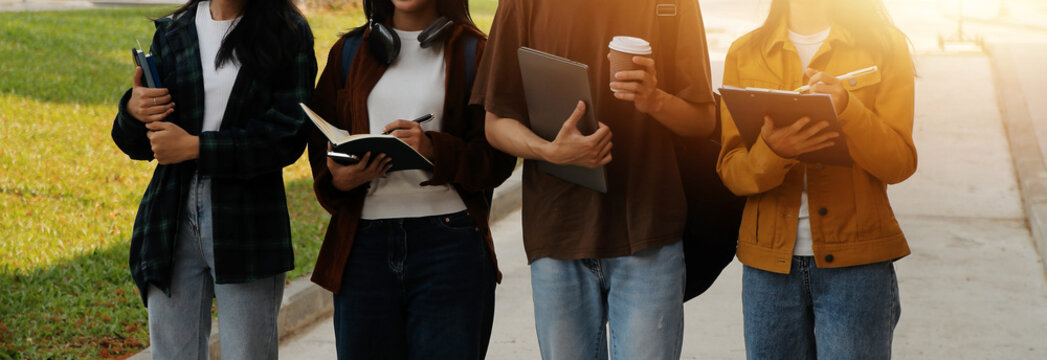 Happy students walking together on university campus, chatting and laughing outdoors after classes