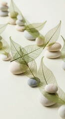 Stacked smooth river stones with delicate skeleton leaves arranged in a row rocks pebbles