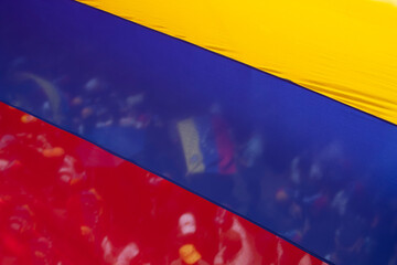 Crowd and flag seen through the transparency of a Venezuelan flag.