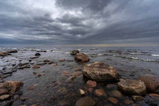 The Gulf of Finland in the eastern part of the Baltic Sea, washes the coasts of Finland, Russia and Estonia. Round granite stones on the sea. Dramatic sky before a thunderstorm.Storm.