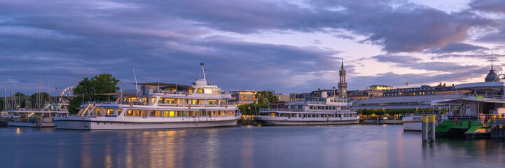 Obraz premium Evening reflections over Lake Constance in Konstanz, Germany with illuminated boats at the local harbor
