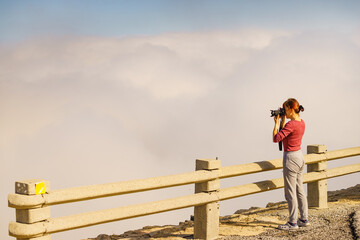 Woman with camera in mountains take travel photo