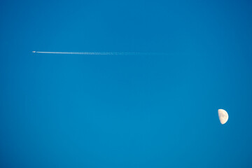 Airplane flying across sky with moon