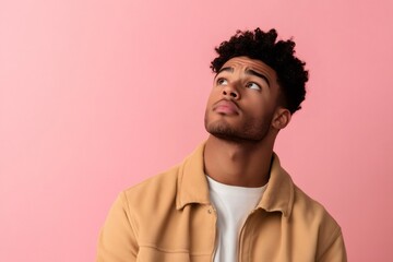 Obraz premium Young black man with a serious expression looking up, seeking inspiration. Thinking about new ideas or solutions