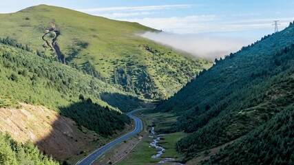 Mountain Highway 318 Winding Through Green Valley Landscape with Blue Sky and White Clouds