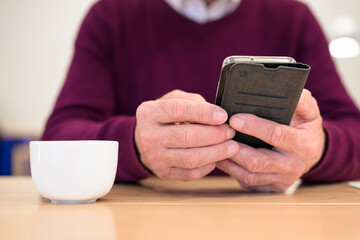 Close-up of senior man using mobile phone at table in office