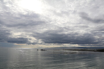 tranquil ocean glistening in the evening light under a dramatic cloudscape 