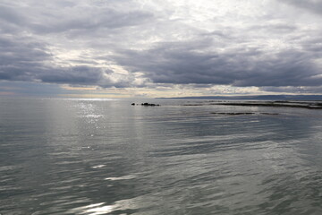 tranquil ocean glistening in the evening light under a dramatic cloudscape 
