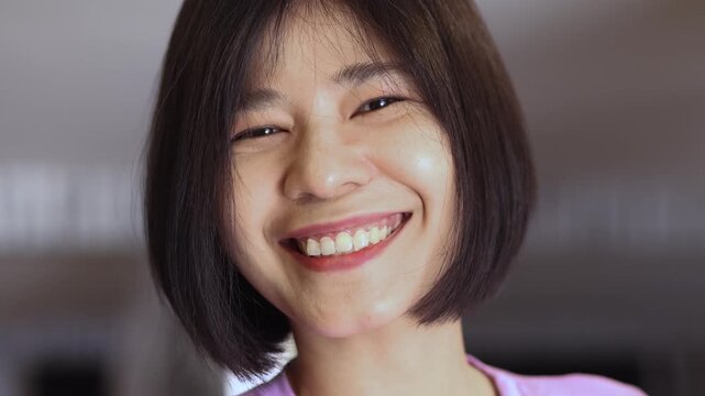 young woman smiling confidently while flipping her new short hair, asia woman, showing happiness, freshness, and natural beauty, the art of hairstyling