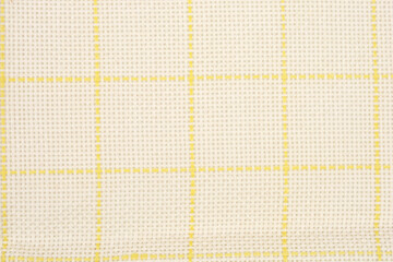 A close-up shot of a light beige woven fabric or canvas texture overlayed with a regular yellow grid pattern