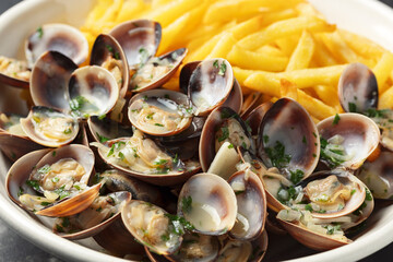 Steamed Clams with herbs and French fries in a white plate