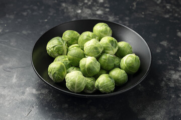 Fresh Brussels Sprouts in a black plate. Healthy food.