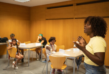 Afro African american teacher actively explaining concepts to diverse students in a classroom
