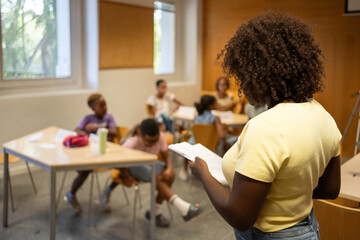 Afro Black teacher reading to diverse students learning in a classroom setting