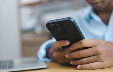 Business person using smartphone for online communication and digital work with laptop on desk