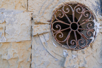 Rustic Iron Grate with Circular Motif on Weathered Stone Wall